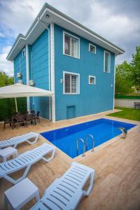 萨潘贾Antonelya Home的蓝色的房子,前面设有一个游泳池