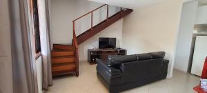 阿拉亚尔-杜卡布Beach House uma casa no Caribe brasileiro的客厅配有黑色真皮座椅和楼梯