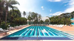伊瓜苏Hotel Nacional Inn Foz do Iguaçu的一个带白色椅子的游泳池和一个游泳池