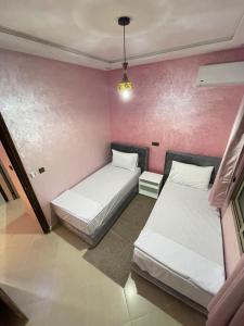 拉希迪耶IGHIZ INN resort的配有粉红色墙壁的客房内的两张床