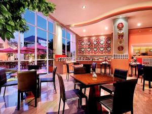 库塔巴厘岛库塔宜必思酒店的餐厅设有桌椅和窗户。