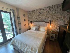 SanteaguedaIncreíble Loft Completo en Val'Quirico的一间卧室设有一张大床和石墙
