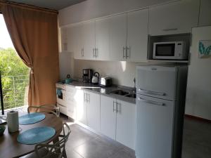 罗萨里奥Departamento Vera Mujica 3 cochera propia incluida的厨房配有白色橱柜、桌子和冰箱。