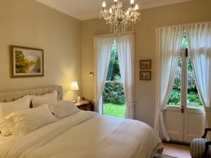 黑荒地Rowan Brae Historic Guesthouse的一间卧室配有一张带吊灯的床和两个窗户。
