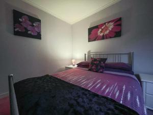 金洛赫伯维Bervie Road Cottage的一间卧室配有一张带紫色棉被的床