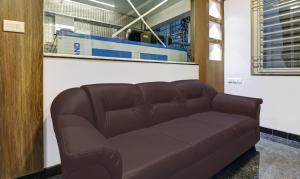 班加罗尔Treebo Trend Elite Heritage的一张棕色皮沙发坐在房间里