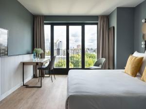 柏林numa I Arc Rooms & Apartments的配有一张床、一张书桌和一扇窗户的酒店客房