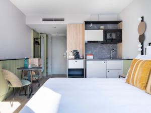 柏林numa I Arc Rooms & Apartments的一间带白色床的卧室和一间厨房