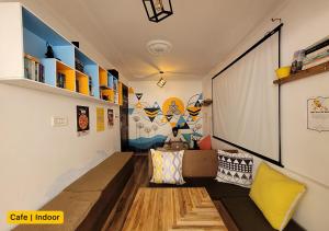 麦罗肯机Young Monk Hostel & Cafe Dharamkot的一间配备有沙发和大屏幕的客房