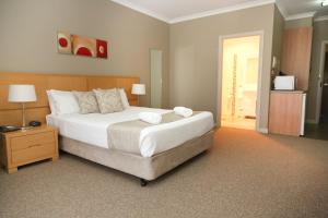 格里菲斯Centrepoint Apartments Griffith的一间卧室配有一张白色大床和床头柜