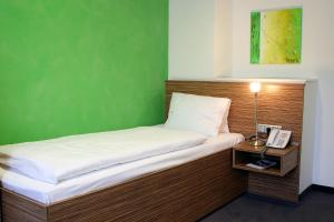 米尔茨楚施拉格温克勒酒店及餐厅的一张带电话和绿色墙壁的床
