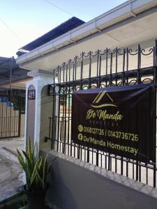 山打根De'Manda Homestay的建筑物一侧的标志