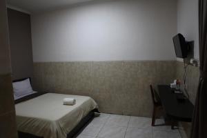 井里汶Rahayu Hotel Cirebon的一间卧室配有一张床、一张书桌和一台电视
