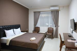 井里汶Rahayu Hotel Cirebon的酒店客房配有一张床、一张书桌和一台电视。