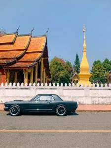 琅勃拉邦Villa Senesouk Luang Prabang的停在大楼前的街道上的一辆蓝色汽车