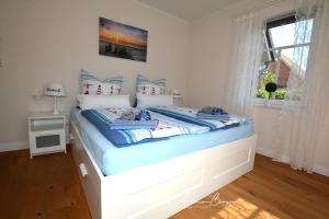 SüdbrookmerlandPension Lütje Huske Zimmer 2的一间卧室配有一张带蓝色床单的床和一扇窗户。