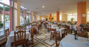 兰哈龙安达卢西亚酒店的餐厅设有白色的桌椅和窗户。