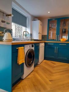 波特兰Sea View Cottage in Dorset, Portland的厨房配有蓝色橱柜和洗衣机。