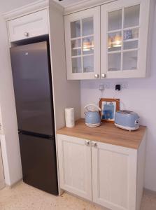 马萨尔福恩Lucky Summer Marsalforn Holiday Apartment的厨房配有黑冰箱和白色橱柜。