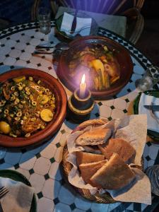 姆哈米德Erg Chegaga Camp Excursions的一张桌子,上面放着两盘食物和一支蜡烛