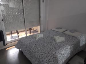 罗萨里奥Alquiler Temporario Rosario 4的卧室配有带枕头的床铺和窗户。