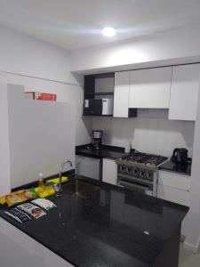 罗萨里奥Alquiler Temporario Rosario 4的厨房配有白色橱柜和黑色台面