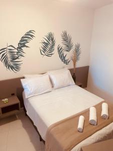 弗洛里亚诺波利斯Pousada Hoffmann的卧室配有一张铺有白色床单的床,墙上挂着棕榈叶。