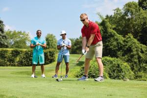 桑达斯基Sawmill Creek by Cedar Point Resorts的三人在高尔夫球场打高尔夫