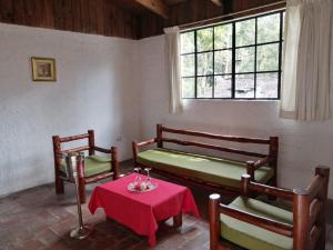 科万Posada Montaña del Quetzal的一间设有两张长椅、一张桌子和一个窗户的房间