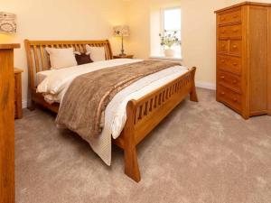 拉克霍尔The Cottage At Briarlea的一间卧室配有一张大型木床和一个梳妆台。