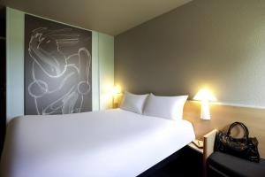 莱斯卡尔宜必思保罗莱斯卡尔酒店的卧室配有一张白色床,墙上挂有绘画作品