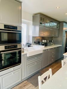 伦敦Hameway House- Stunning 4 bedroom house with a spacious kitchen的厨房配有不锈钢用具和灰色橱柜