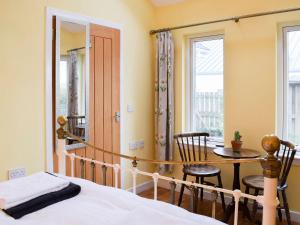 GartmorePuddingstone Cottage的一间卧室配有一张床、一张桌子和一个窗户。
