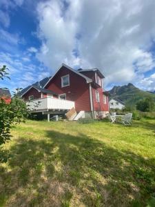 斯沃尔韦尔Unique and charming house at the foot of Lofoten's highest mountain的一座大红色房子,在院子里设有长凳