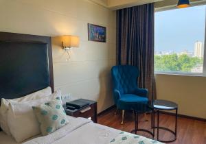 勒克瑙Comfort Hotel Vista的酒店的客房 - 带一张床、椅子和窗户