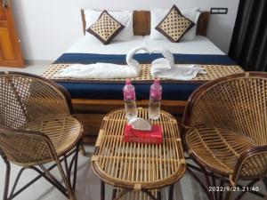 瓦尔卡拉Devi Kripa Residency的配有带椅子的床和桌子上的2瓶水的房间