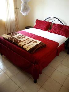 LiraWestcliff Hotel的一张带红色枕头的床和一张毯子