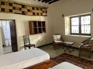 莫桑比克岛Casa Fabula的一间卧室设有两张床、两把椅子和两个窗户。
