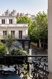 巴黎皮嘉尔大酒店的阳台配有桌子和长椅,大楼