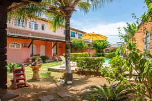 布希奥斯Flats vila bela Búzios的庭院里种着棕榈树,还有黄伞