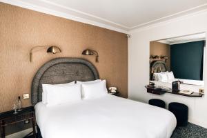巴黎皮嘉尔大酒店的一间卧室设有一张大床和一个大镜子
