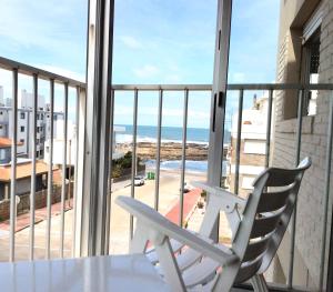 埃斯特角城ap frente mar Península Punta Del Este的白色椅子,位于海景阳台上