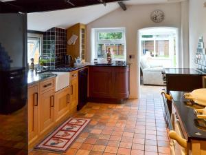 MundfordTree Tops Cottage的厨房配有木制橱柜和瓷砖地板。