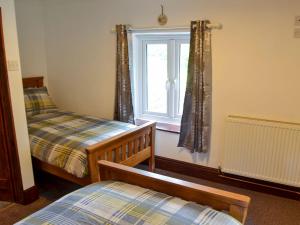 MundfordTree Tops Cottage的一间卧室设有两张床和窗户。