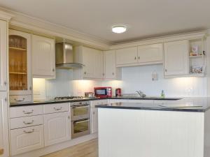 纽基Seaview Apartment - 21 Spinnakers的白色的厨房配有白色的橱柜和柜台。