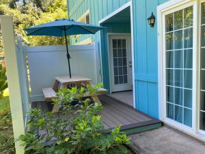 哈纳Heavenly Hana Paradise的蓝色的房子,配有长凳和雨伞