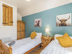 贝克韦尔Spa Cottage的卧室设有两张床铺和蓝色的墙壁