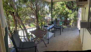 布里斯班Rose'n Daves Guest House的阳台配有桌椅和树木。