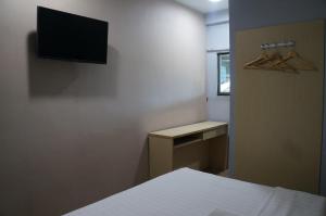 哥打京那巴鲁Unikarya Lodge的卧室配有一张床,墙上配有电视。