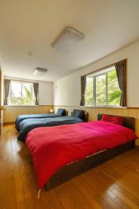 轻井泽Kanra-gun - House / Vacation STAY 2833的一间大卧室,配有两张带红色床单的床